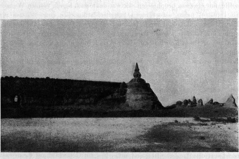 Photograph of the ruined walls of Khara-Khoto with a stupa standing above the sand